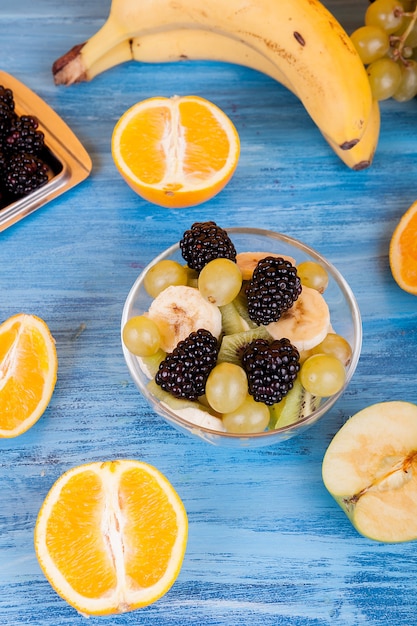 Vista superior de frutas variadas sobre la mesa de madera. Bayas, naranjas y uvas en la mesa de madera azul