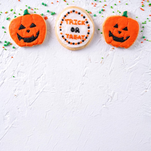 Vista superior de las galletas de azúcar glas decoradas festivas de Halloween sobre fondo blanco