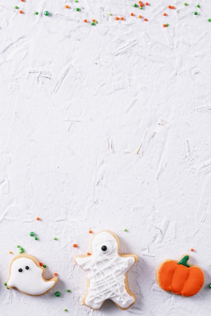 Foto vista superior de las galletas de azúcar de pan de jengibre decoradas con hielo festivo de halloween sobre un fondo blanco con espacio de copia y diseño plano