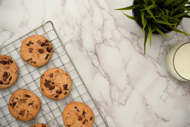 Vista superior Galletas de chispas de chocolate recién horneadas en una rejilla de enfriamiento de alambre sobre fondo de mármol blanco