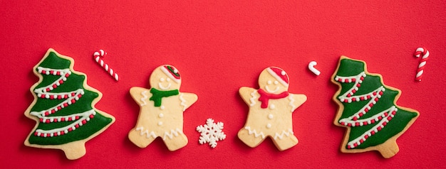 Foto vista superior de galletas de jengibre de navidad decoradas con adornos en el fondo de la mesa roja con espacio de copia, concepto de celebración navideña.