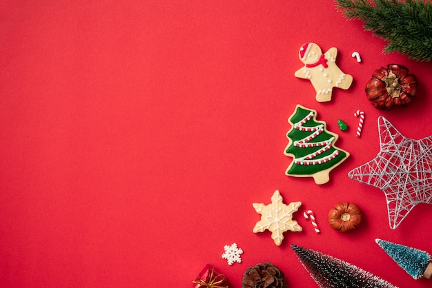 Vista superior de galletas de jengibre de Navidad decoradas con adornos en el fondo de la mesa roja con espacio de copia, concepto de celebración navideña.
