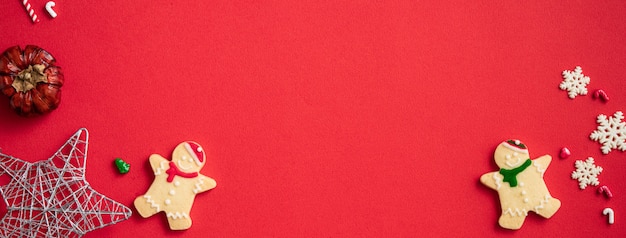 Vista superior de galletas de jengibre de Navidad decoradas con adornos en el fondo de la mesa roja con espacio de copia, concepto de celebración navideña.