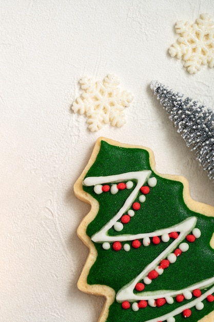 Vista superior de galletas de jengibre de Navidad decoradas con adornos sobre fondo de mesa blanca con espacio de copia, concepto de celebración navideña.