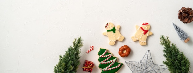 Vista superior de galletas de jengibre de Navidad decoradas con adornos sobre fondo de mesa blanca con espacio de copia, concepto de celebración navideña.