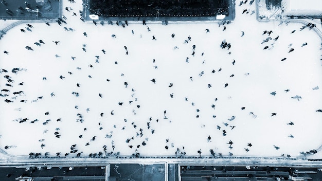 Vista superior de la gente patinando en una gran pista de hielo al aire libre en el día de invierno, vista aérea de drones, vuelo sobre cr