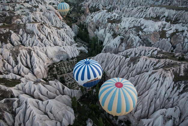 Vista superior de globos rayados volando en el valle entre rocas en Capadocia