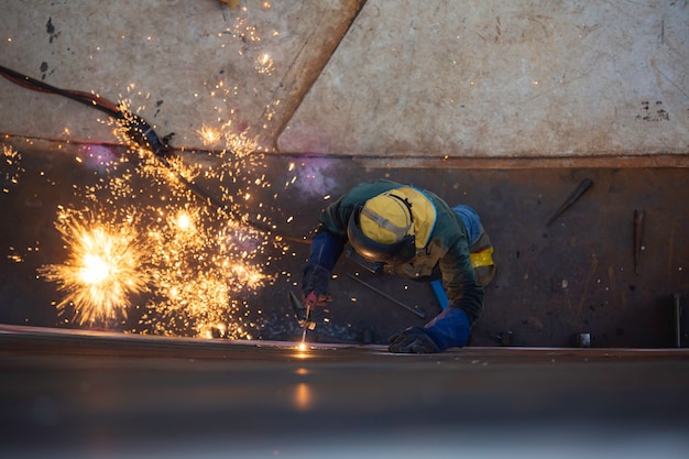 Vista superior goivagem soldagem faísca fogo soldador industrial usar máscara de proteção de segurança construção reparo tanque solda a óleo para a peça em especificações confinadas