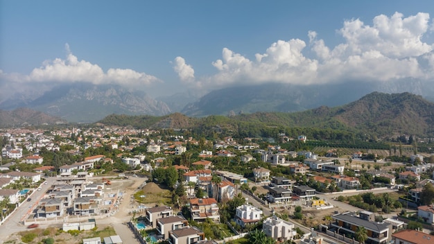 Vista superior de la gran ciudad Casas residenciales Urbanización Montañas verdes y nubes al fondo Fotografía