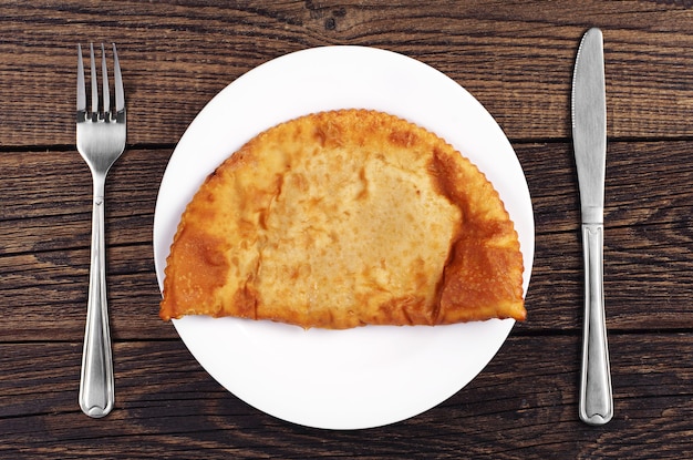 Vista superior de grandes empanadas y cubiertos en mesa de madera