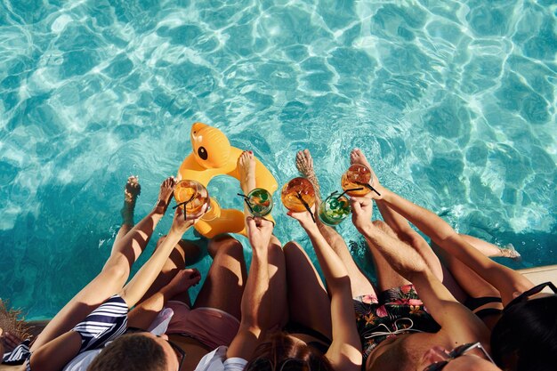 Vista superior del grupo de jóvenes felices que se divierten en la piscina durante el día