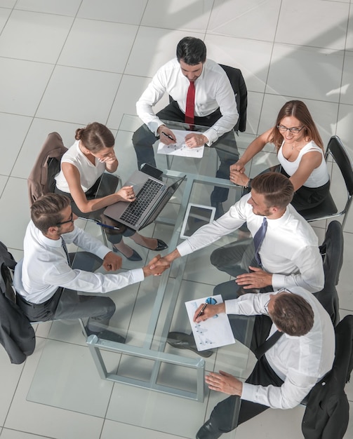 Foto vista superior del grupo multiétnico de personas de negocios emergentes en una reunión de lluvia de ideas en el moderno y luminoso interior de la oficina