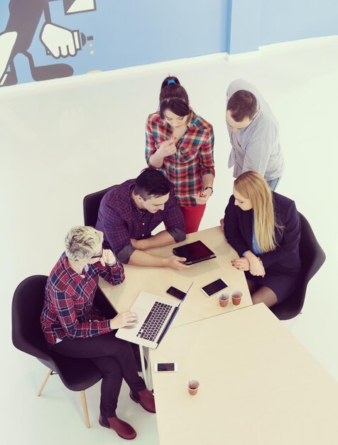 Vista superior del grupo multiétnico de personas de negocios emergentes en una reunión de lluvia de ideas en el moderno y luminoso interior de la oficina