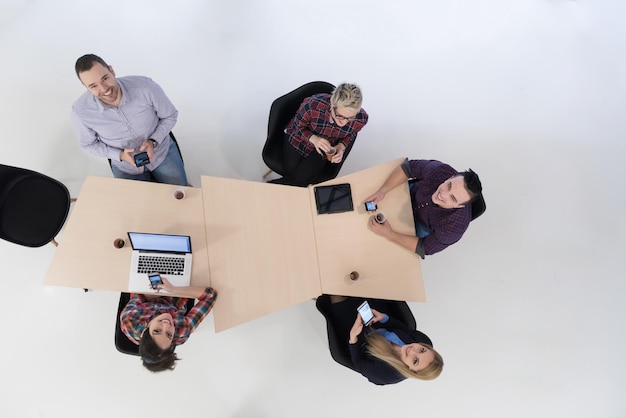 Vista superior del grupo multiétnico de personas de negocios emergentes en una reunión de lluvia de ideas en el moderno y luminoso interior de la oficina