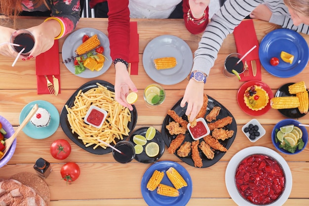 Vista superior de un grupo de personas cenando juntas mientras se sientan en una mesa de madera. Comida en la mesa. La gente come comida rápida