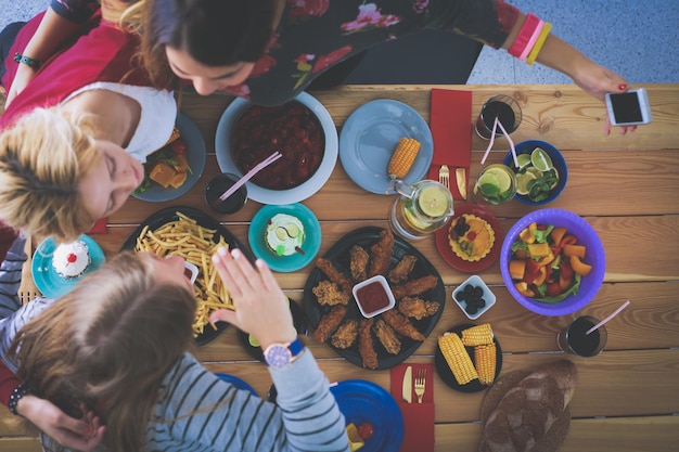 Vista superior del grupo de personas cenando juntos mientras están sentados en la mesa de madera Comida en la mesa La gente come comida rápida