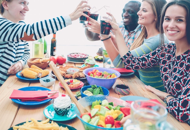 Vista superior del grupo de personas cenando juntos mientras están sentados en la mesa de madera Comida en la mesa La gente come comida rápida
