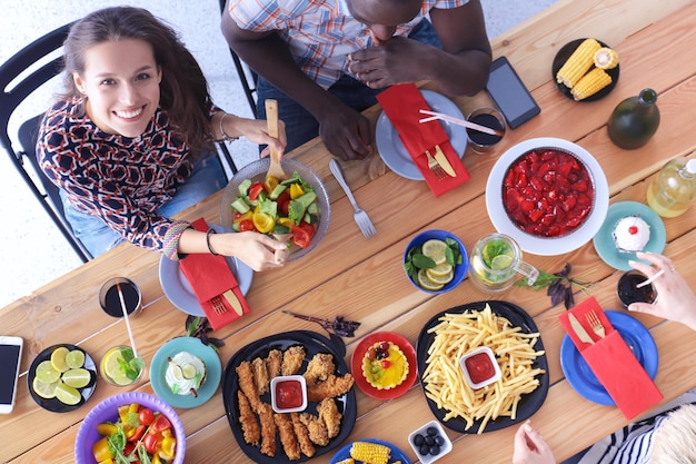 Vista superior del grupo de personas cenando juntos mientras están sentados en la mesa de madera Comida en la mesa La gente come comida rápida