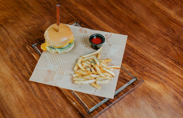 Vista superior de una hamburguesa de queso con papas fritas servida en una mesa de madera Una deliciosa hamburguesa con patatas fritas en una tabla de madera