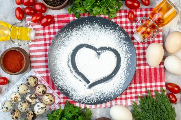 Vista superior de harina blanca en forma de corazón con diferentes ingredientes sobre fondo blanco harina de huevo pastel de leche masa para pastel