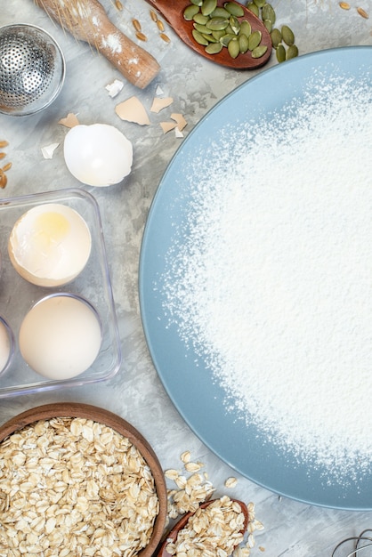 Vista superior de harina blanca con huevos, cereales crudos y semillas sobre fondo blanco pastel de masa de semillas de pastel de leche color maíz