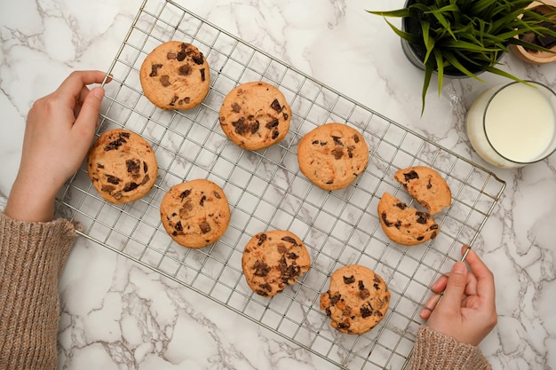 Vista superior Hembra poniendo galletas recién horneadas en la mesa Galletas con chispas de chocolate caseras