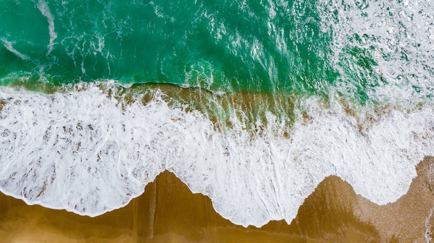 Vista superior de la hermosa playa de arena con agua de mar turquesa.