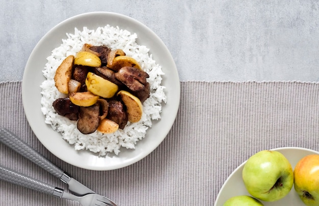 Vista superior de hígado de pollo frito con manzanas servido con arroz blanco en un plato