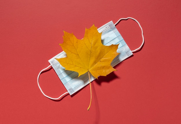 Foto vista superior de la hoja de otoño con máscara médica