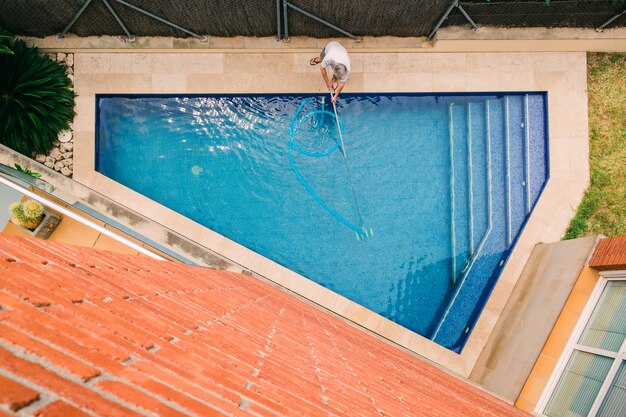 Vista superior del hombre limpiando una piscina