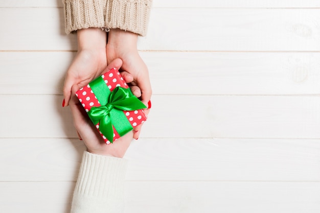 Vista superior de un hombre y una mujer sosteniendo una caja de regalo sobre fondo de madera. Concepto de amor y relación. Copie el espacio.