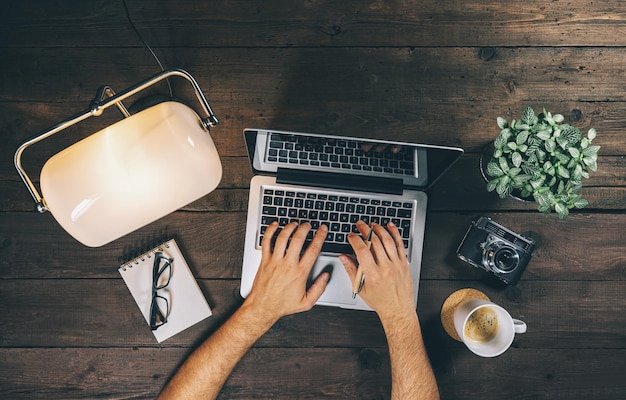 Vista superior del hombre de negocios que usa la computadora portátil en la oficina en casa con la taza de café de la lámpara y la imagen del concepto de vista superior de la cámara