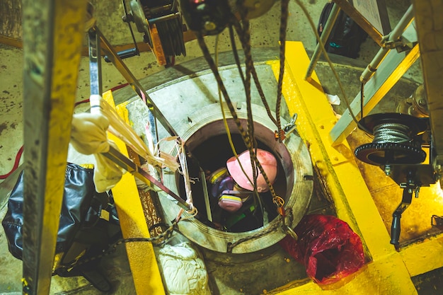 Foto vista superior hombre sube las escaleras hacia el tanque área de químicos de acero inoxidable espacio confinado salva vidas con seguridad de cuerda de rescate