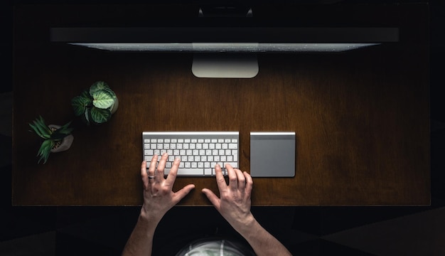 Vista superior de un hombre trabajando en una computadora en una habitación oscura por la noche