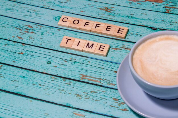 Foto vista superior de la hora del café letras de bloques de madera del alfabeto sobre fondo de madera azul