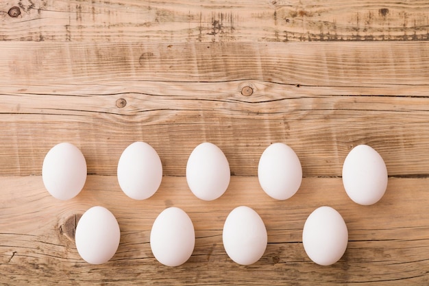 Vista superior de huevos blancos sobre un fondo de madera Fondo festivo de Pascua Endecha plana