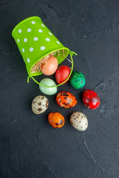 Vista superior de los huevos diseñados en color dentro de la cesta verde fondo oscuro novruz primavera ornamentada concepto de vacaciones horizontal