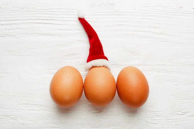 Vista superior de los huevos en la mesa con gorro de Papá Noel