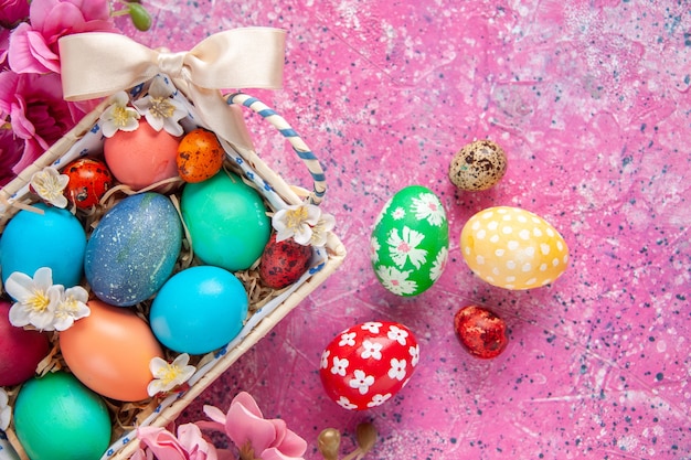 Vista superior de los huevos de pascua de colores dentro de una bonita caja con flores sobre la superficie rosada primavera color colorido concepto de vacaciones de pascua ornamentado