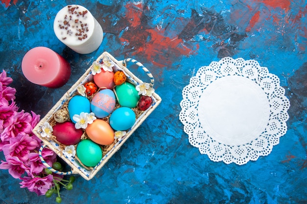 Vista superior de huevos de pascua de colores dentro de una bonita caja sobre superficie azul