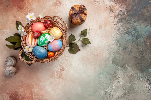 Vista superior de huevos de pascua de colores dentro de la canasta sobre una superficie ligera