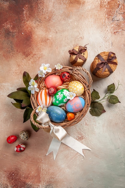 Vista superior de huevos de pascua de colores dentro de la canasta sobre una superficie ligera