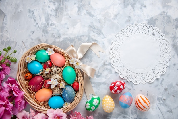 Vista superior de los huevos de pascua de colores dentro de la cesta sobre la superficie blanca primavera colorida vacaciones concepto ornamentado pascua