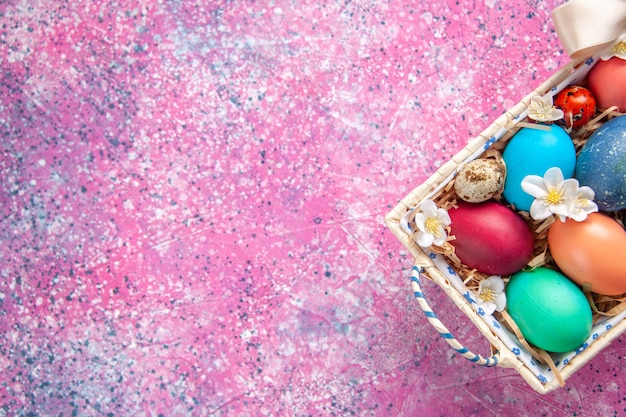 Vista superior de los huevos de pascua de colores dentro de una linda caja en la superficie rosada concepto de color de primavera colorido ornamentado espacio libre de vacaciones de Pascua