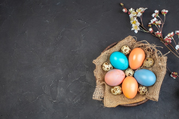 Vista superior de los huevos de pascua de colores dentro de la placa sobre una superficie oscura