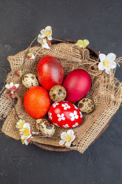 Vista superior de los huevos de pascua de colores dentro de la placa sobre una superficie oscura