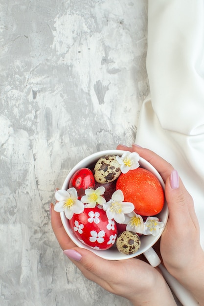 Vista superior de huevos de pascua de colores dentro de la taza blanca sobre la superficie blanca