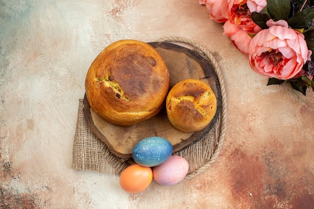 Vista superior de huevos de pascua de colores con horneado de pascua en superficie clara