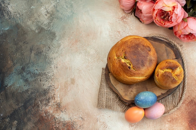 Vista superior de huevos de pascua de colores con horneado de pascua en superficie clara