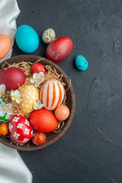 Vista superior de huevos de pascua de colores sobre una superficie oscura